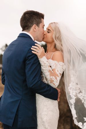 A romantic moment between newlyweds with bride wearing lace dress and flowing veil.