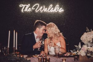 A couple shares an intimate moment at an elegantly decorated table under neon lighting.