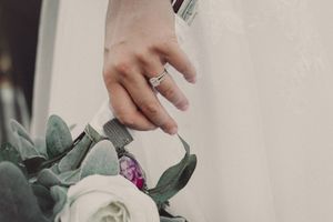 Close-up detail shot of engagement ring with white roses and eucalyptus leaves.
