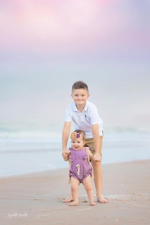 Children playing together on beach during pastel sunset.