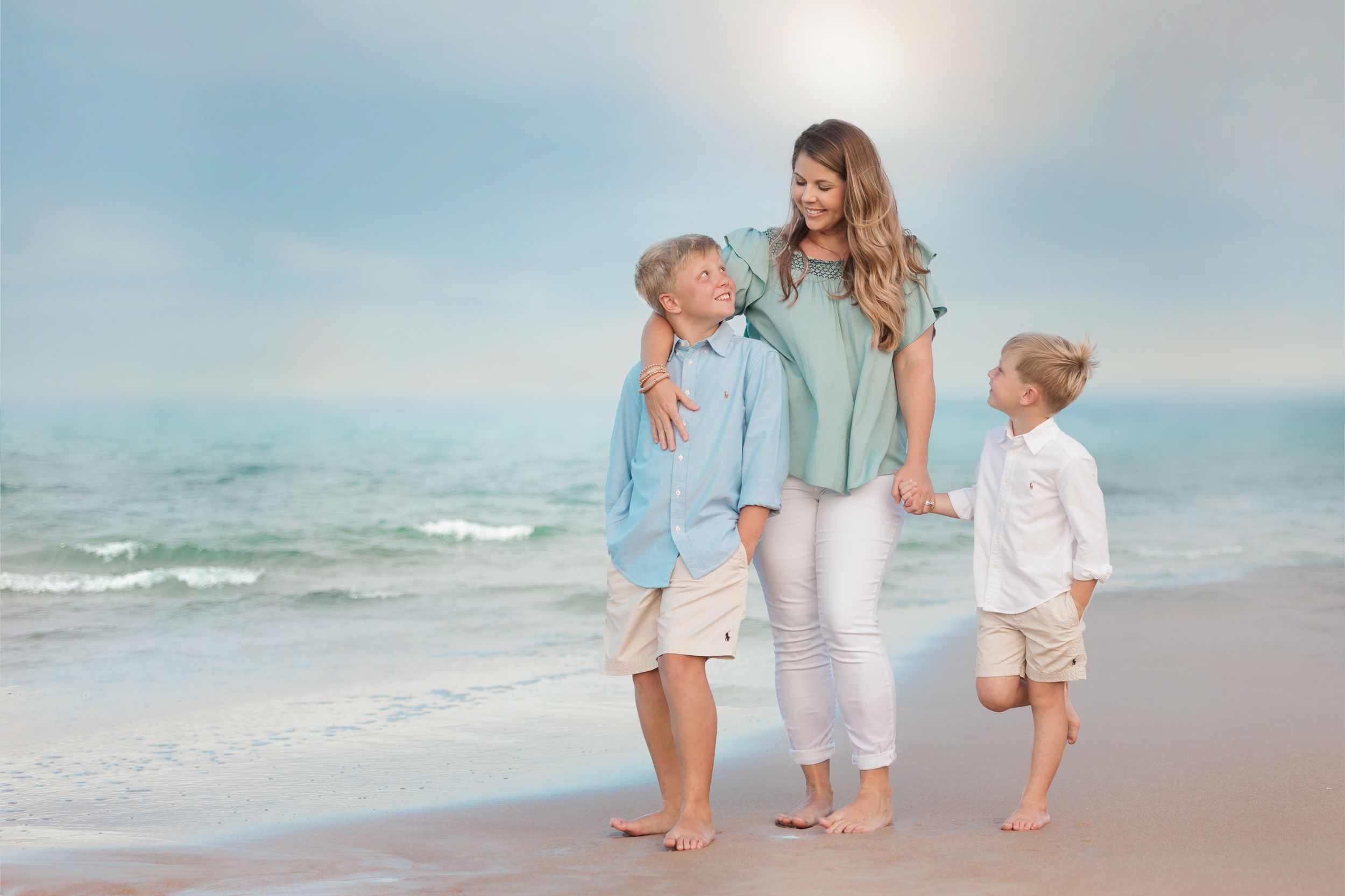 Parent and children walk along beach wearing coordinated blue and white coastal outfits.