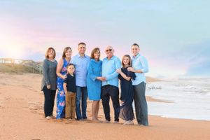 Extended family gathered on beach at sunset for portrait session.