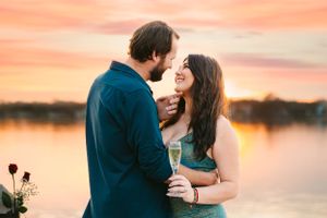 A romantic couple shares an intimate moment at sunset by a lake.