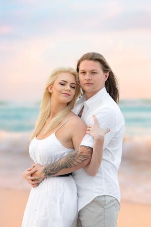 Romantic beach portrait of a couple in white clothing at sunset.