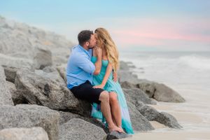 Couple sharing an intimate moment on coastal rocks during sunset photoshoot.