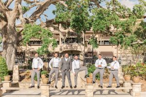 Groomsmen in grey suits posing casually on stone steps.