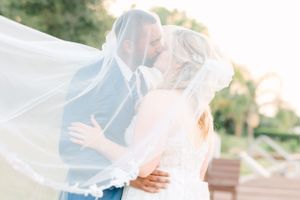 Intimate wedding moment with flowing veil caught in soft natural light.