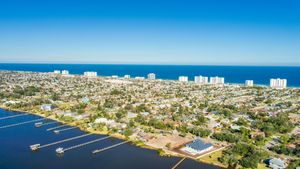Aerial view of coastal city with waterfront properties and boat docks extending into blue water.