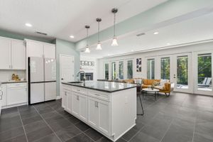 Open concept kitchen and living space with white cabinets, black counters, and modern lighting.