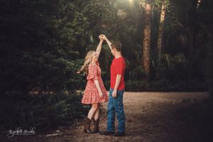 Two figures dance together on a forest path at sunset.