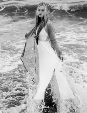 Black and white photo of flowing white dress in ocean waves.