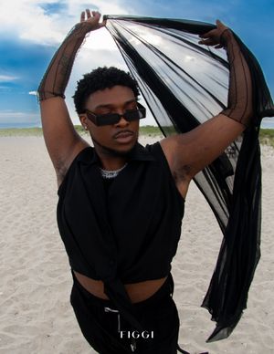 Beach fashion photo with black fabric flowing against blue sky.