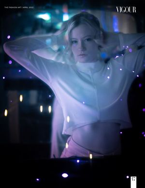 Model in white sweater photographed in dreamy night setting with blue bokeh lights and ethereal glow.