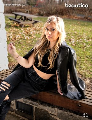 A person in all black attire sits on a wooden bench in an autumn park setting with fallen leaves on the ground.