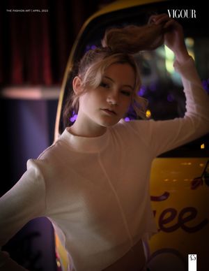 Fashion editorial photo inside a car at night with moody lighting, white sweater and bokeh lights in background.