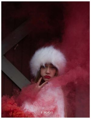 A figure in a white furry hat and coat stands in dramatic pink smoke creating a moody winter fashion scene.