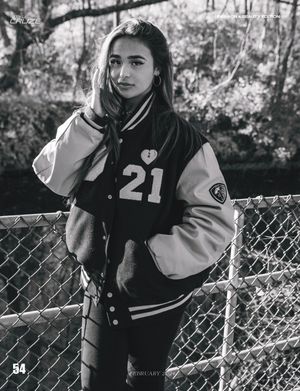 Black and white portrait features varsity jacket with number 21 against chain link fence backdrop.