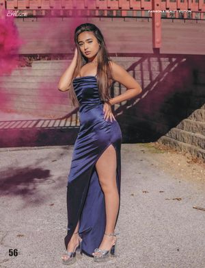 Fashion model in navy blue satin gown poses with pink smoke effect in urban setting.