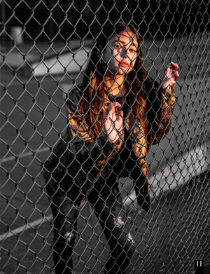 A selective color photo shows a figure in black against a chain link fence with orange lighting effects.
