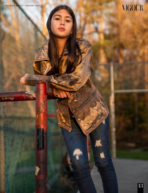 Fashion model in gold metallic jacket and ripped jeans poses against autumn background during outdoor photoshoot.