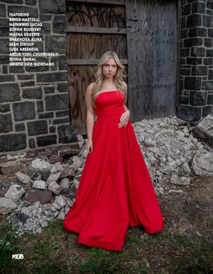 A stunning red ball gown stands out against a rustic stone wall and weathered wooden door backdrop.