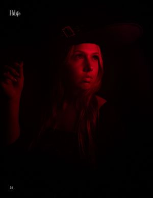 Moody red-lit portrait with dark aesthetic featuring black hat and dramatic shadows.
