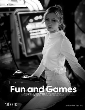 Black and white editorial photo of a model in all white attire posing in what appears to be a TV or film studio setting.
