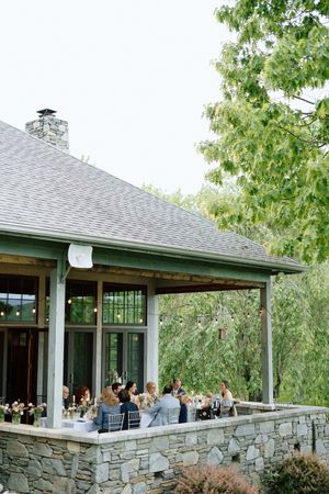 Stone patio wedding reception venue with covered dining area surrounded by lush trees.