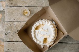 White wedding cake with 'Just Married' text in a simple brown box.