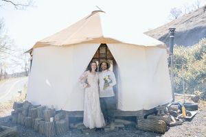 Bridal party poses in front of a white canvas tent in a mountain setting.