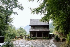 Rustic log cabin with stone path and mountain views in a serene forest setting.