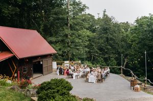 Rustic outdoor wedding reception on a mountain deck with string lights and wooden tables.