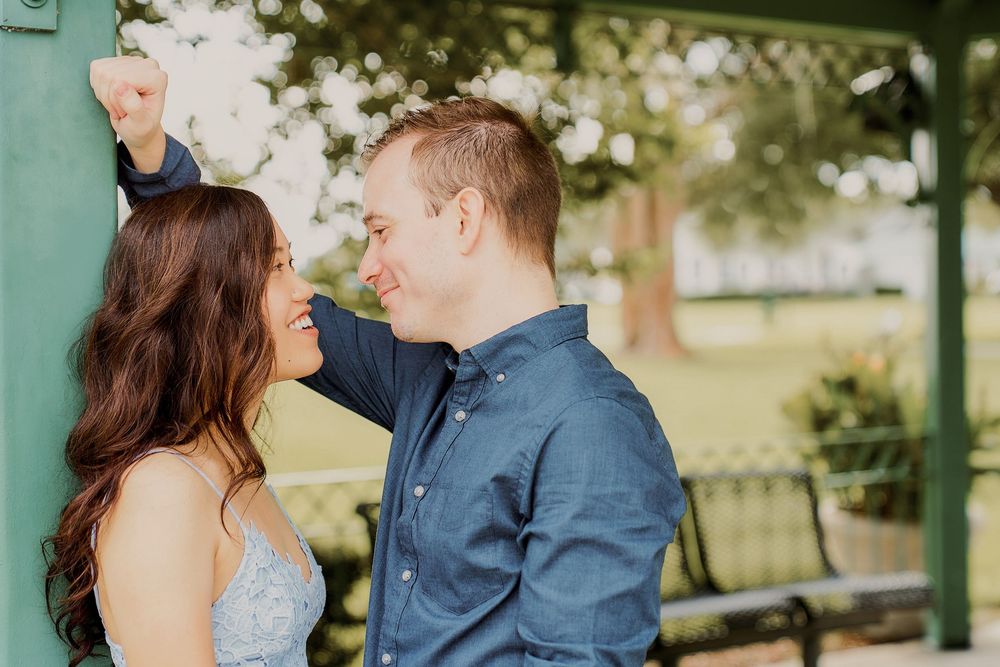 A couple in formal attire shares a romantic moment in an outdoor garden setting during their wedding photoshoot.