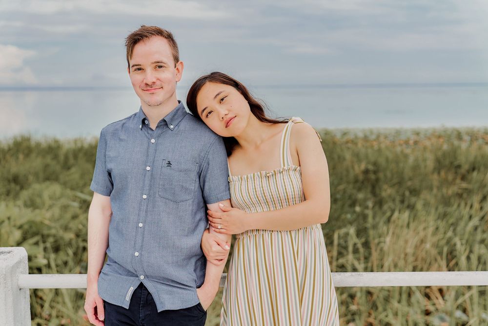 A couple shares tender moments in a grassy field during their engagement photo session at sunset.