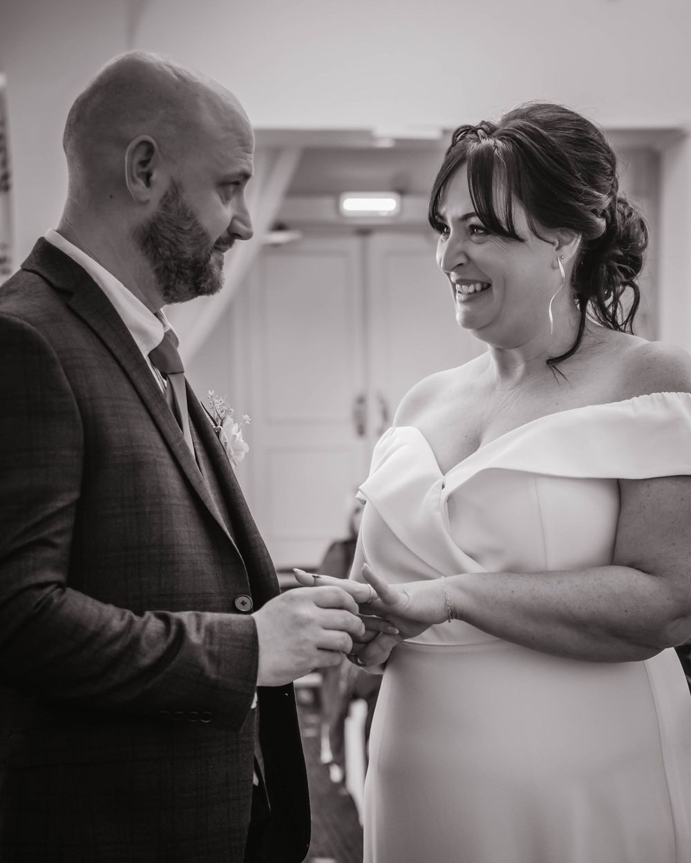 A joyful couple shares a candid moment during their wedding ceremony, with the bride in an elegant off-shoulder gown.
