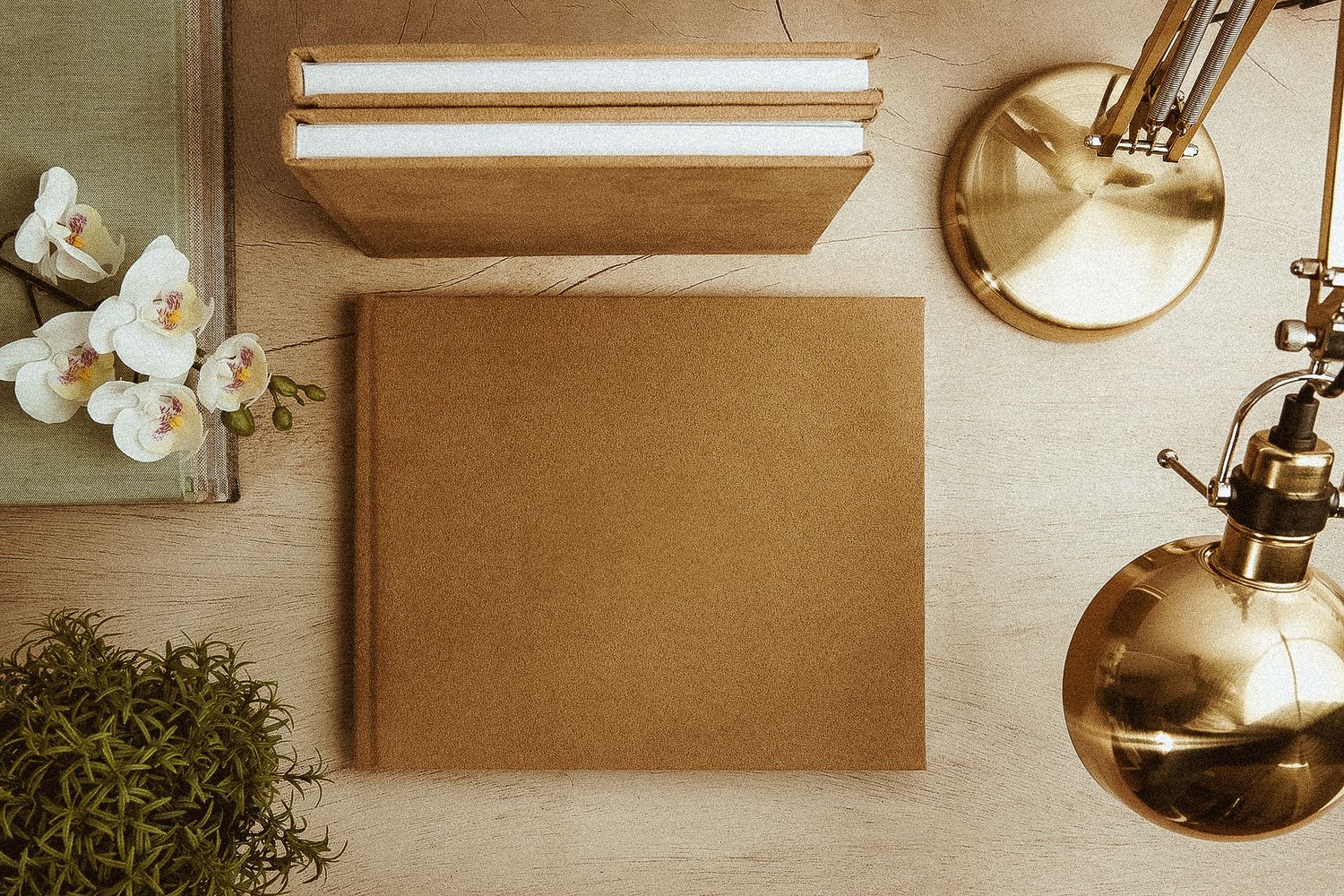 Blank brown kraft paper on white desk with gold lamp and white flowers in vintage style workspace setup.
