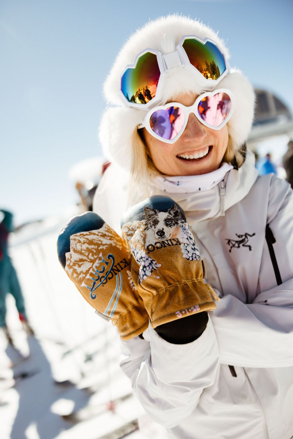 Winter sports enthusiast in white ski gear and colorful goggles shows excitement on snowy slope.
