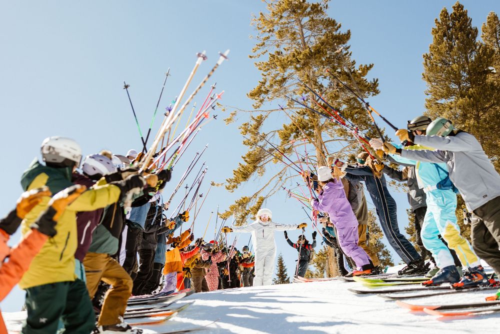 Colorful lineup of skis and snowboards against bright blue winter sky.