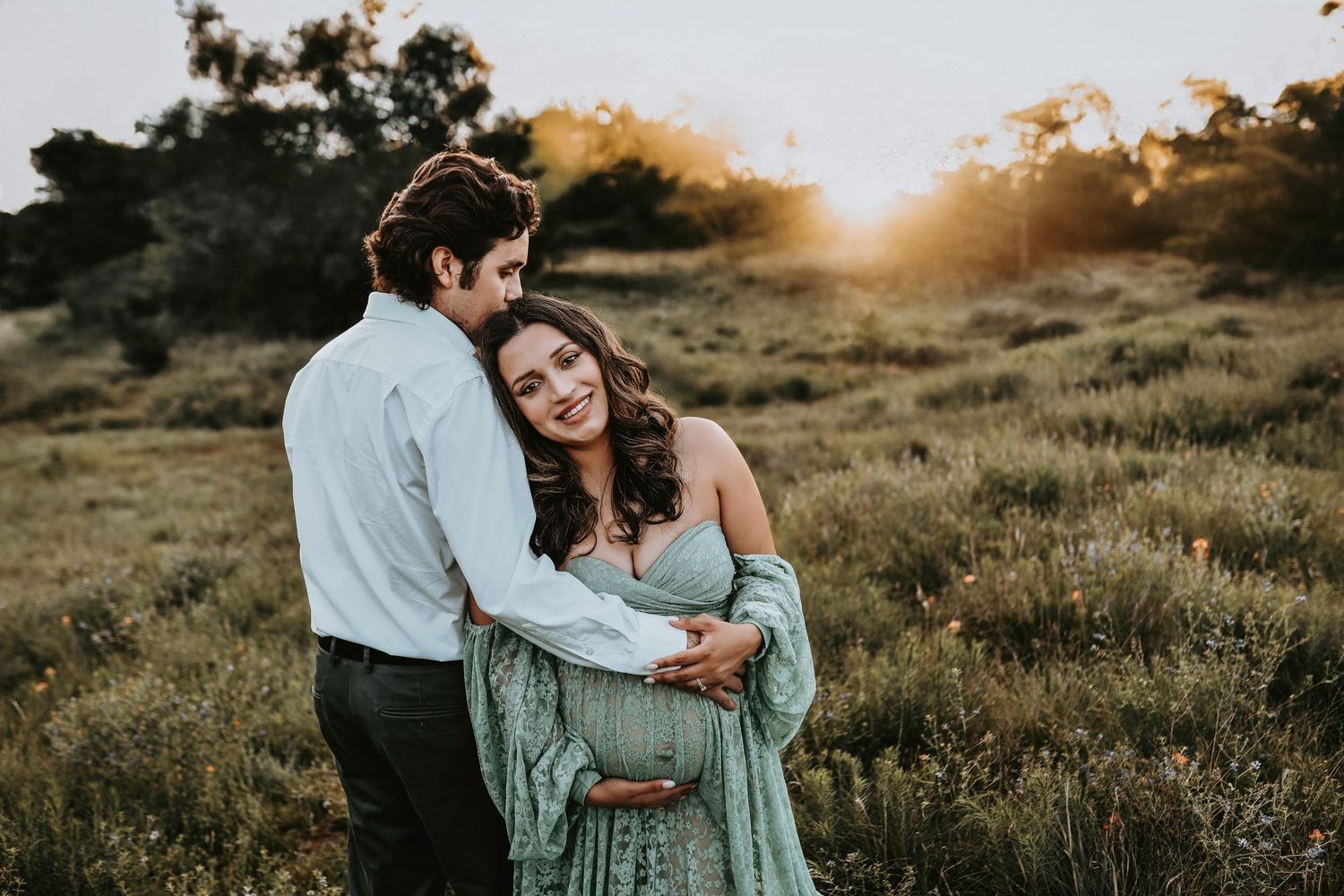 mother and father embrace as mother holds her belly for maternity photos on lake grapevine