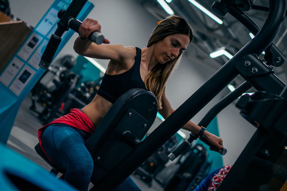 Woman performing intense workout with weight equipment in modern gym environment.