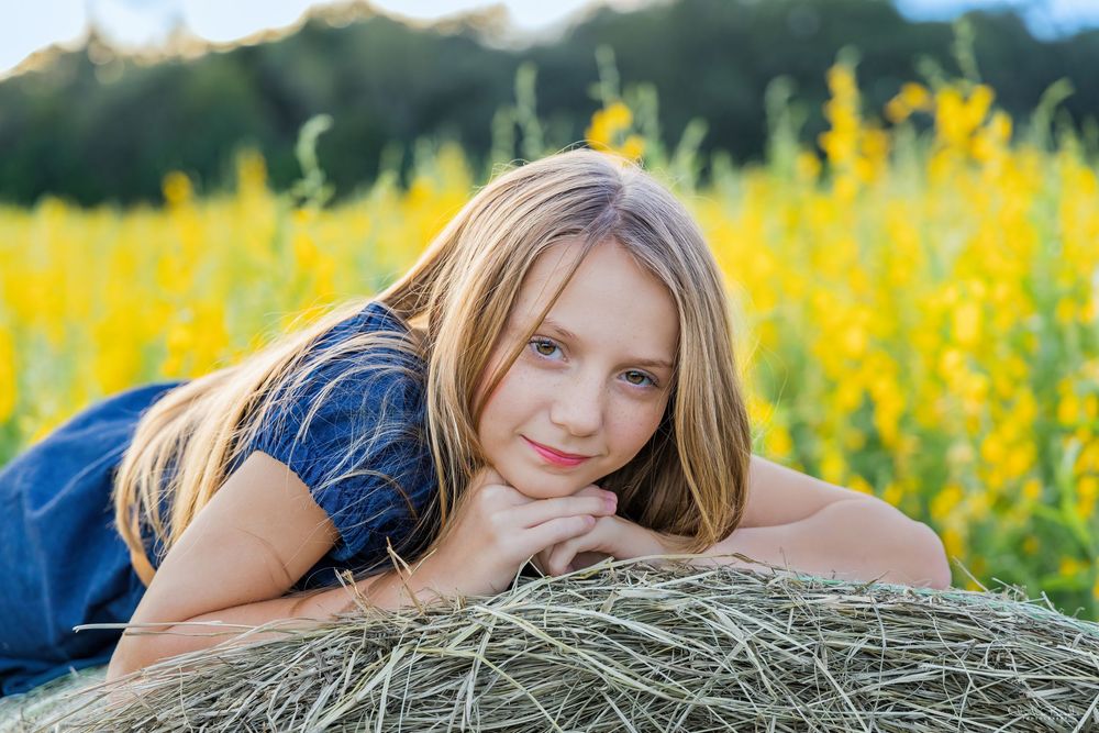 Relaxed summer portraits in a field with hay bales and warm evening light.