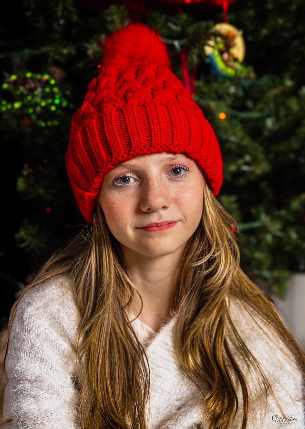 Portrait series showing a festive holiday look with a red knit hat and white sweater.