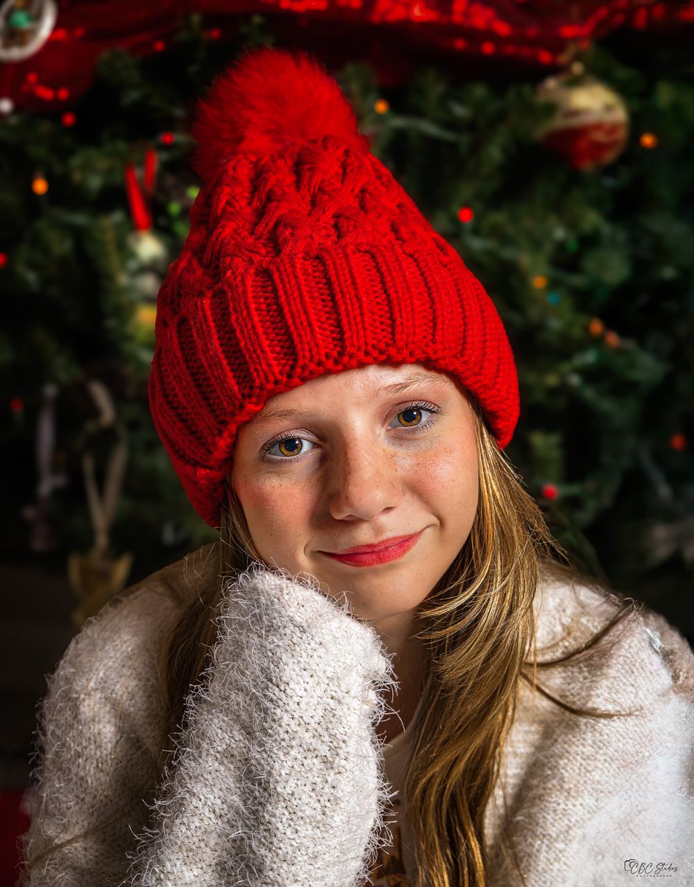 Close-up holiday portraits featuring bright red knit hat and white winter sweater.