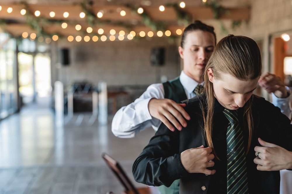 A formal tie adjustment in an elegant venue with string lights in the background.