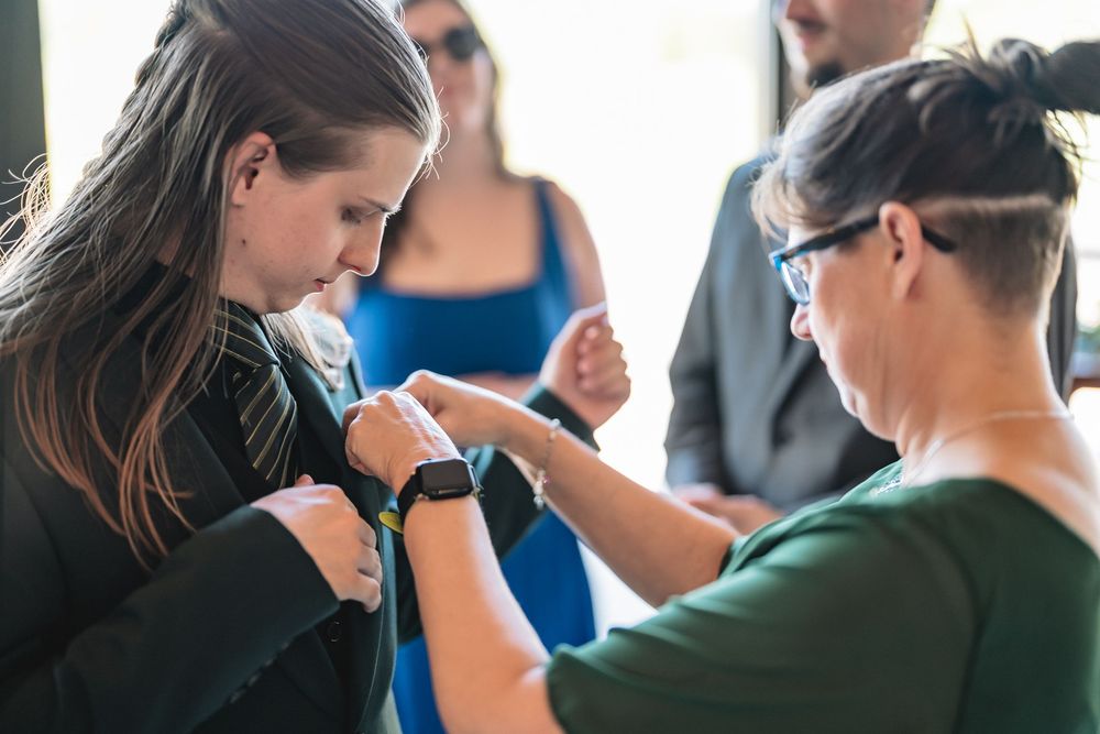 Two people wearing smartwatches synchronize their devices while others look on in the background.