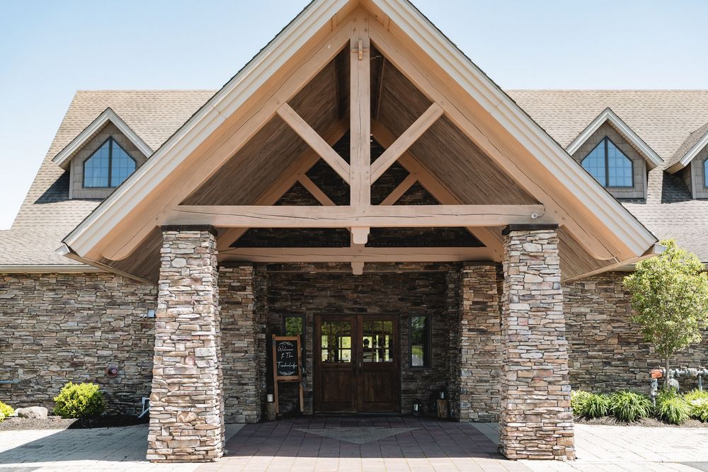 Stone and timber lodge entrance featuring a grand peaked roof and rustic architectural details.