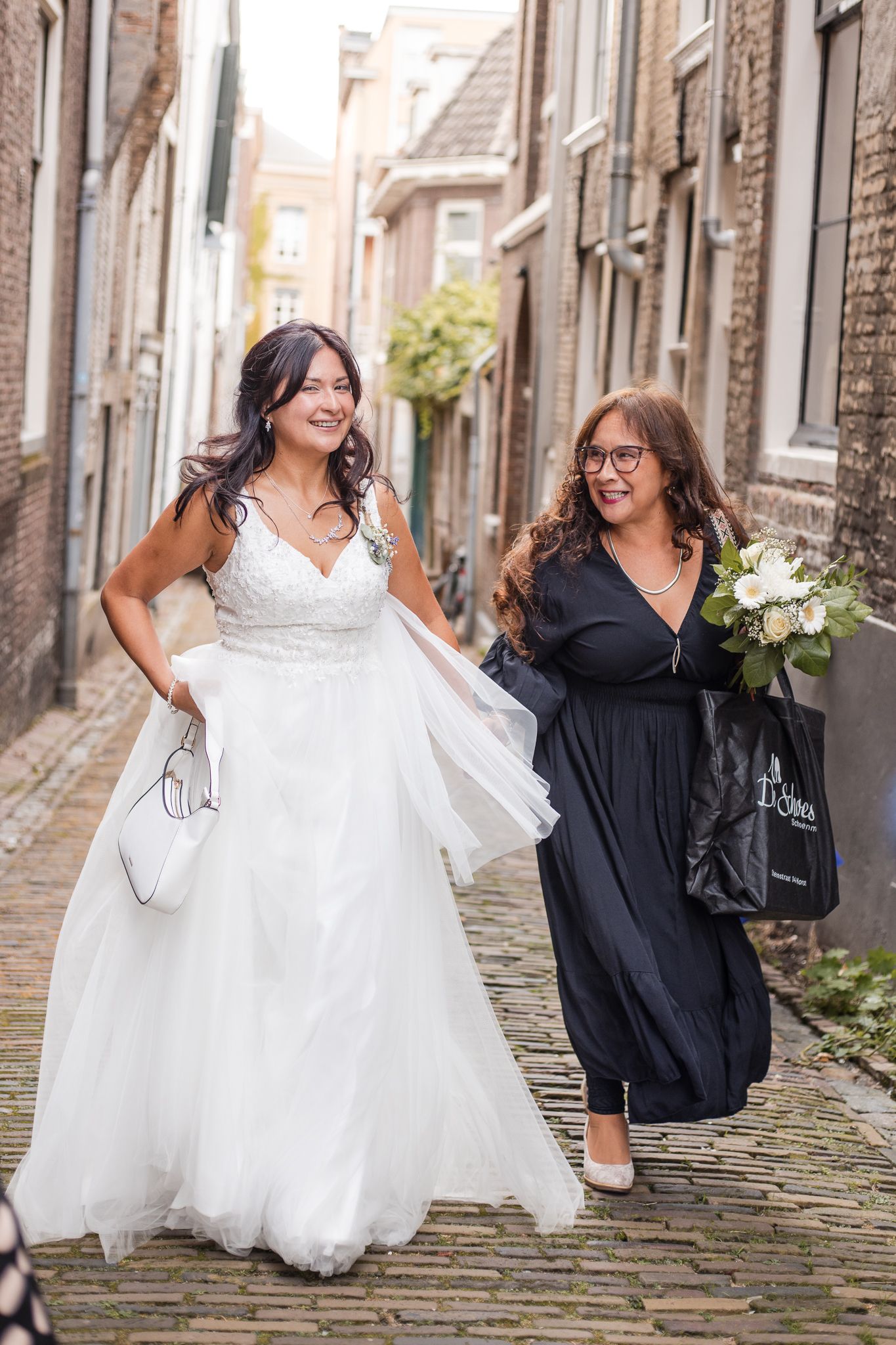 Bride and her mother walking together on a cobblestone street after a gemeente wedding in Gorinchem