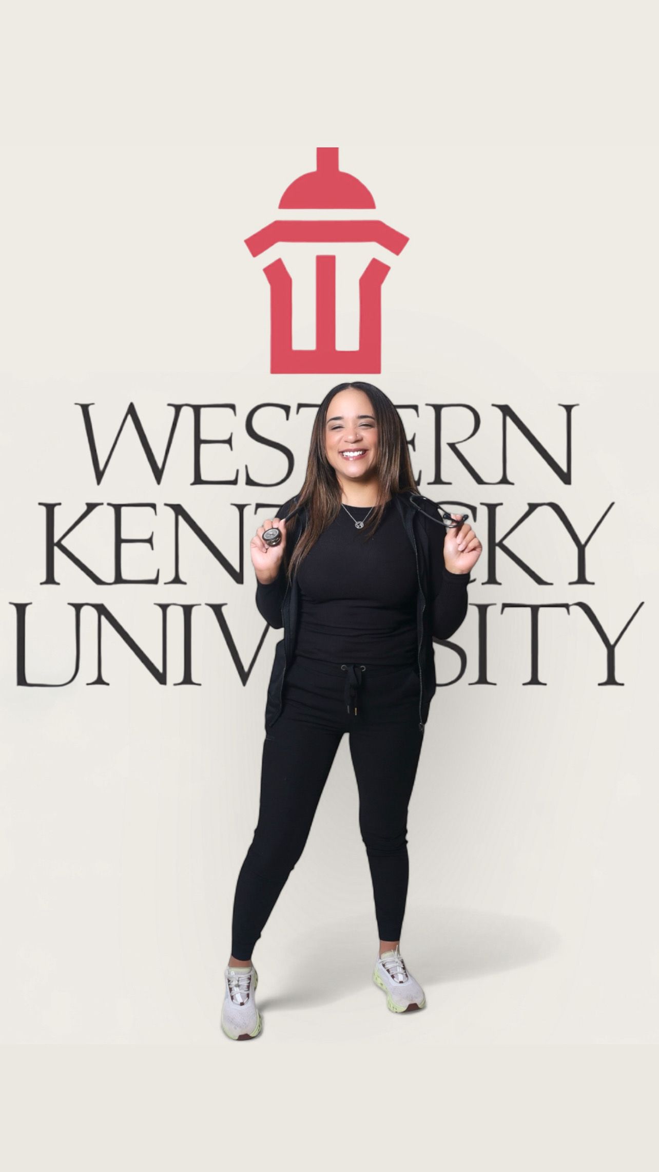 Smiling woman in black athletic wear poses in front of Western Kentucky University logo backdrop.