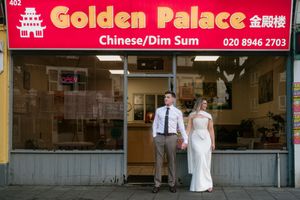 A couple in wedding attire stands outside Golden Palace Chinese restaurant in London.