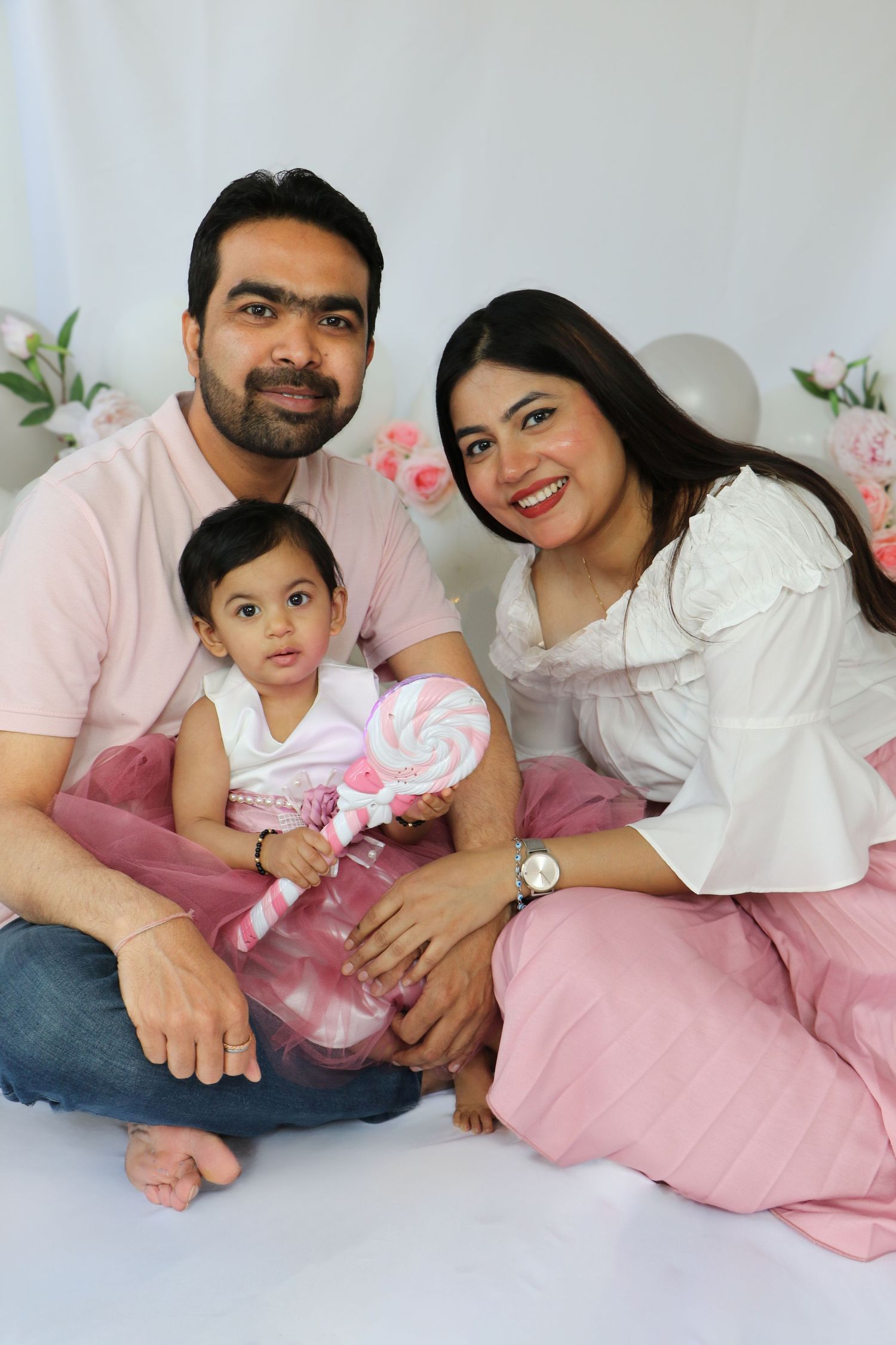 Family smiling together in coordinated pink and white outfits. Coventry Cake Smash Photographer. First Birthday.